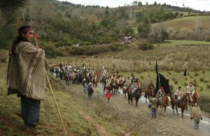Members of the Mapuches Indians Movement ride their horses as a Chilean Mapuche stands guard during the burial ceremony of Jaime Facundo Mendoza Collio, who was killed during clashes with riot police, near Temuco city, some 680 km (422 miles) south of Santiago, August 16, 2009. Collio, 24, died on August 12, 2009 after being shot during clashes with police in a land dispute in southern Chile, local media reported. REUTERS/Jose Luis Saavedra (CHILE POLITICS CONFLICT)